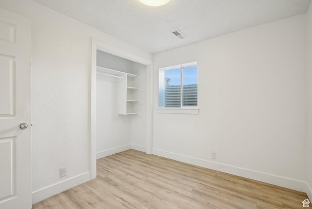 unfurnished bedroom featuring a closet, light wood-type flooring, visible vents, and baseboards
