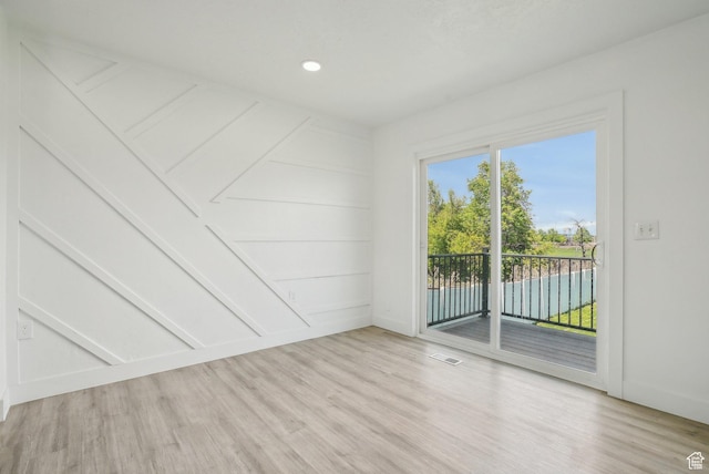 empty room with light wood finished floors, visible vents, baseboards, and recessed lighting