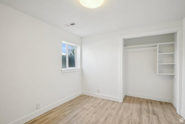 unfurnished bedroom featuring light wood finished floors, a closet, visible vents, and baseboards