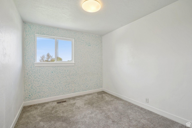 carpeted empty room with wallpapered walls, visible vents, and baseboards