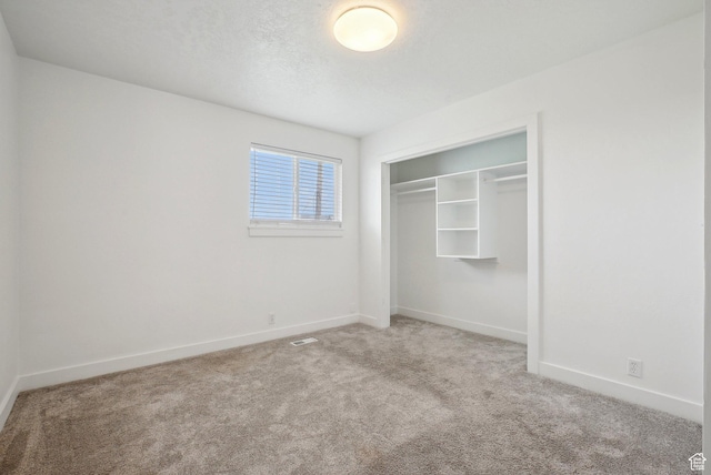 unfurnished bedroom with carpet flooring, a closet, visible vents, and baseboards