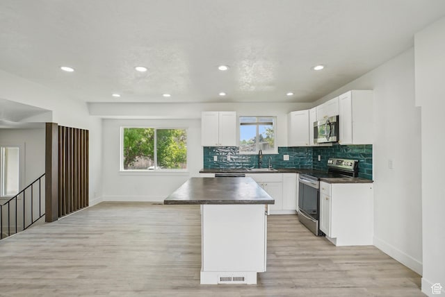 kitchen with recessed lighting, a sink, a kitchen island, dark countertops, and stainless steel appliances