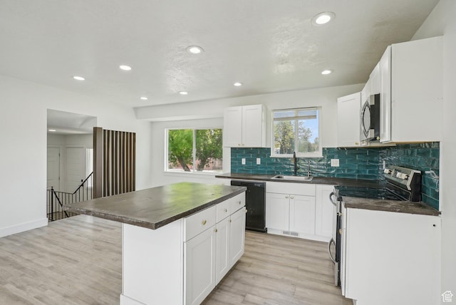 kitchen with dark countertops, stainless steel appliances, light wood-style flooring, and a sink