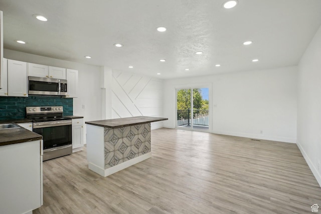 kitchen featuring stainless steel appliances, recessed lighting, light wood-style flooring, white cabinets, and dark countertops