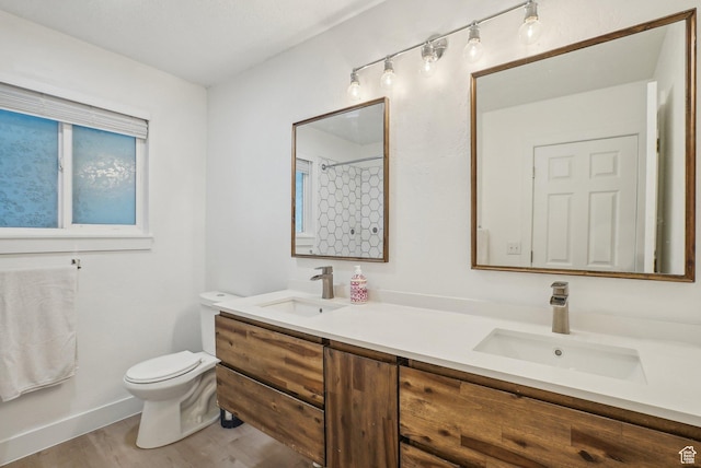 bathroom featuring double vanity, toilet, wood finished floors, and a sink