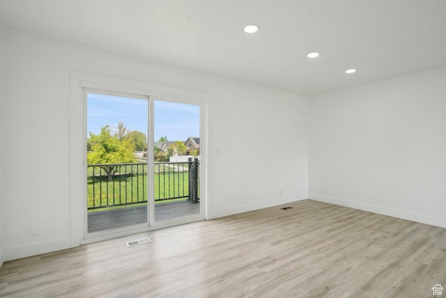 empty room with light wood finished floors, visible vents, baseboards, and recessed lighting