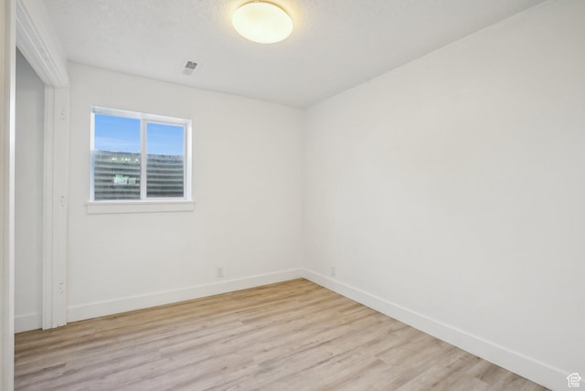 spare room featuring baseboards, light wood-style floors, and visible vents
