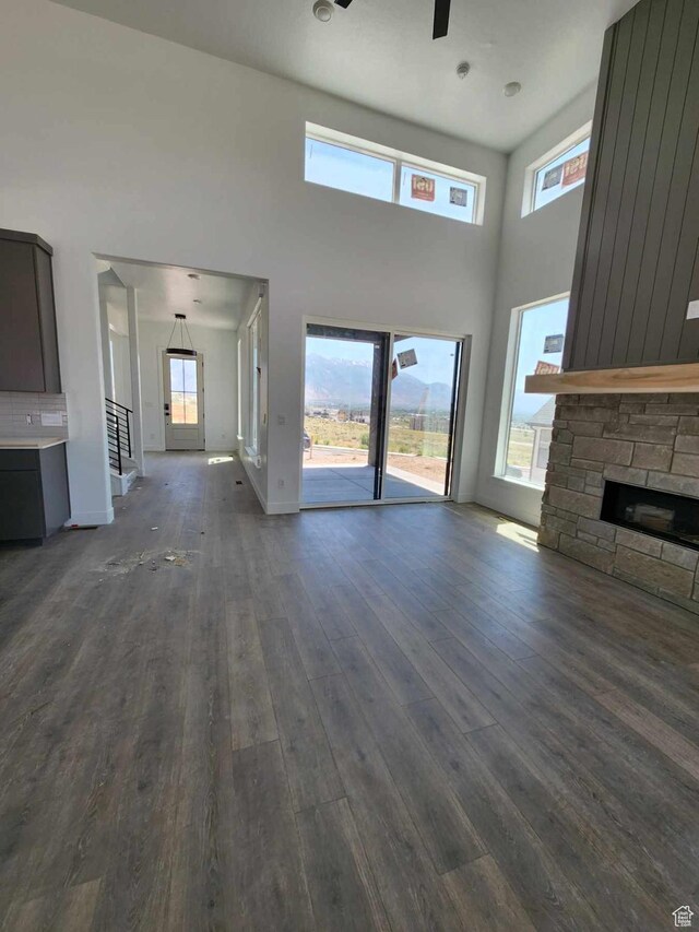 4197 N Maple Hollow Dr Unit 120, Lehi, UT 84043 - unfurnished living room featuring dark wood-style floors, healthy amount of natural light, a fireplace, a towering ceiling, and a ceiling fan