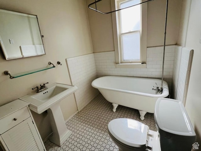full bathroom featuring tile walls, a freestanding bath, and toilet