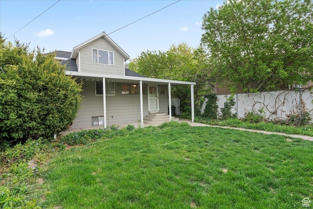 rear view of property with fence, a yard, entry steps, and a shingled roof