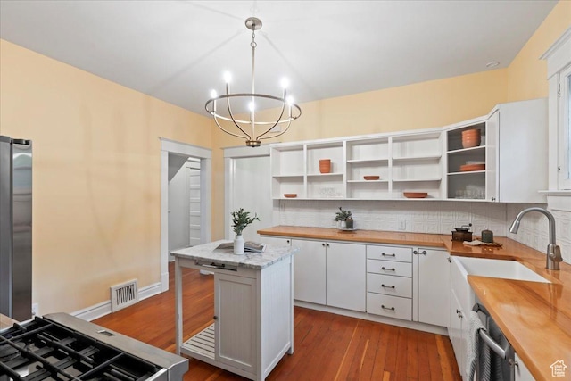 kitchen with visible vents, wooden counters, freestanding refrigerator, and a sink