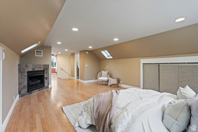 bedroom featuring visible vents, baseboards, light wood finished floors, and vaulted ceiling with skylight