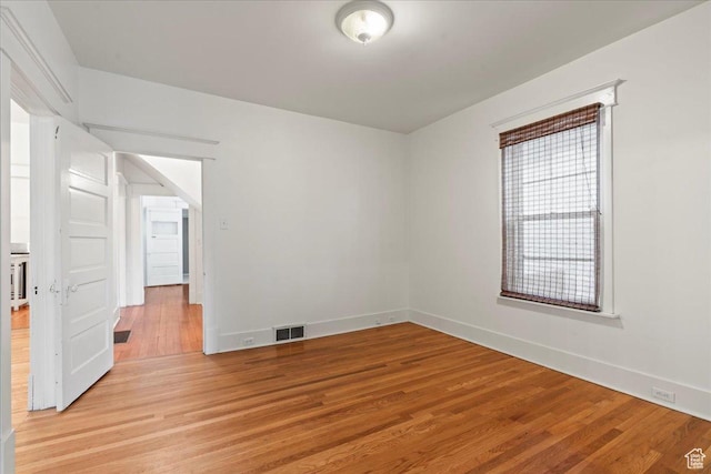 unfurnished room with visible vents, light wood finished floors, and baseboards