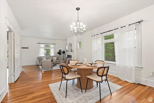 dining space with baseboards, a notable chandelier, and light wood-style floors