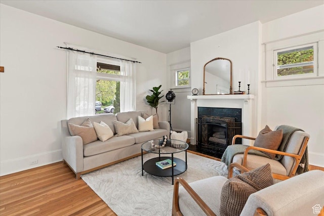 living room with a fireplace with flush hearth, a healthy amount of sunlight, light wood-type flooring, and baseboards