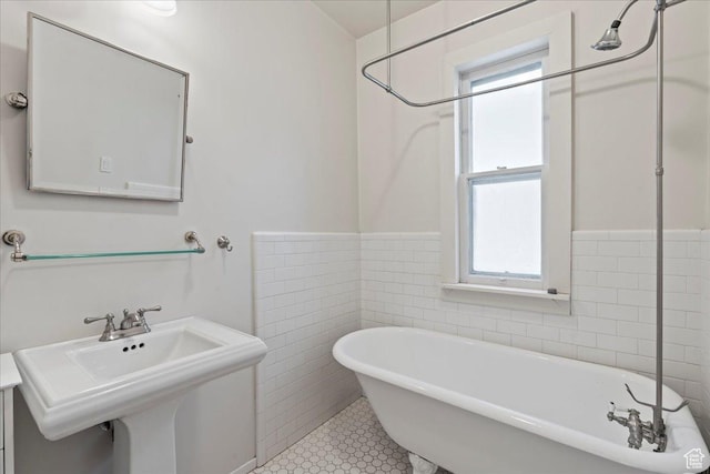 bathroom with tile walls, a freestanding bath, a wainscoted wall, and a sink