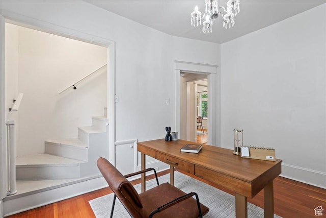office area featuring baseboards, wood finished floors, and an inviting chandelier