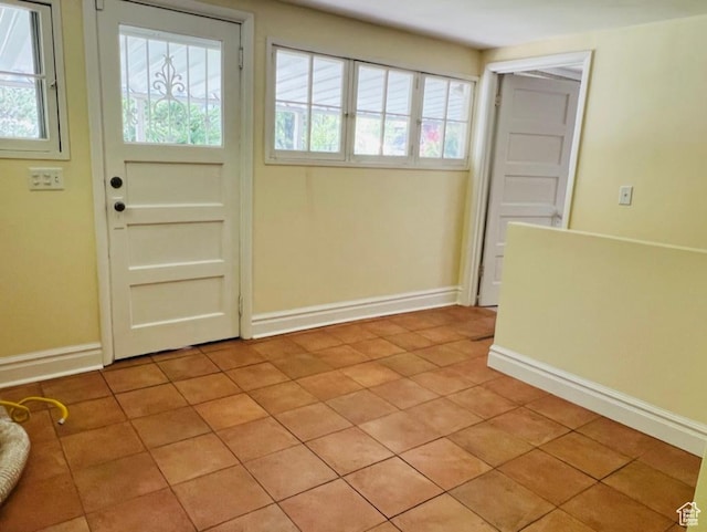 doorway to outside featuring baseboards, a healthy amount of sunlight, and light tile patterned floors