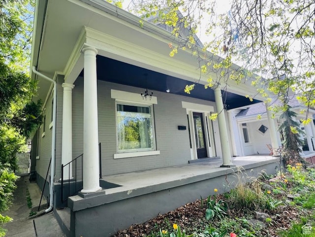 rear view of house featuring covered porch and brick siding