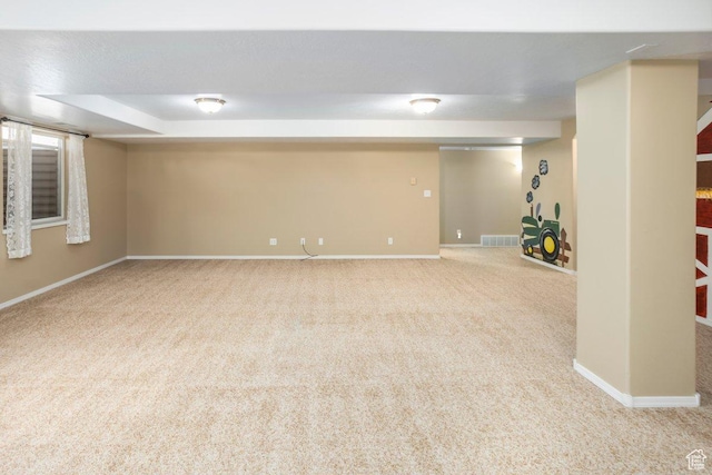 finished below grade area with baseboards, visible vents, and carpet