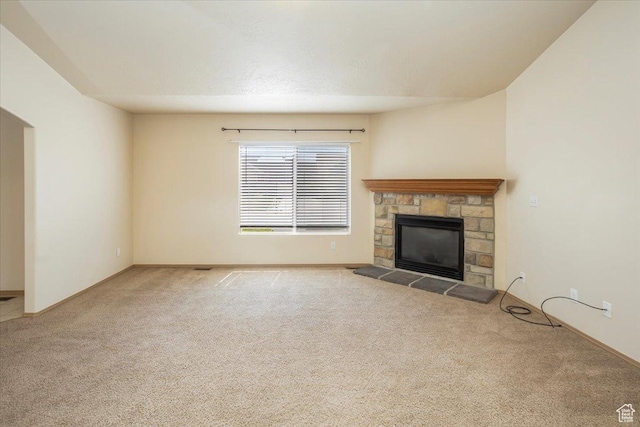 unfurnished living room featuring baseboards, a stone fireplace, and carpet
