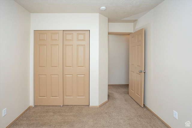 unfurnished bedroom with baseboards, a closet, and light colored carpet