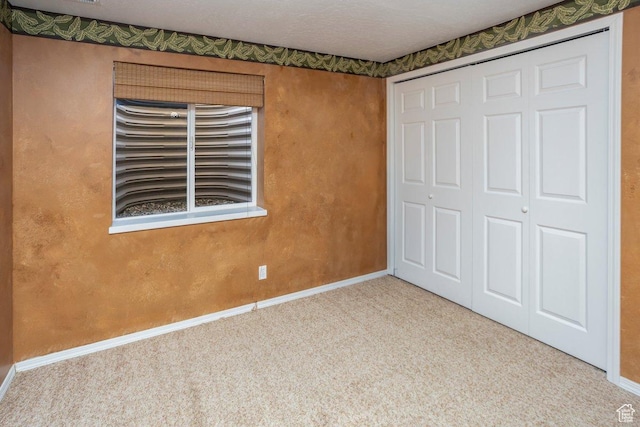unfurnished bedroom with baseboards, carpet flooring, and a closet