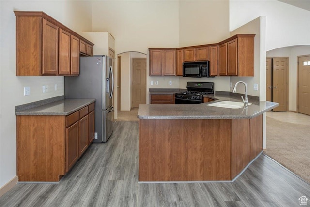 kitchen featuring arched walkways, a high ceiling, a sink, and black appliances