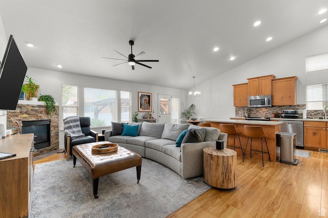1962 E Meadow Downs Way S, Cottonwood Heights, UT 84121 - living room with ceiling fan with notable chandelier, a wealth of natural light, a stone fireplace, and light wood-type flooring
