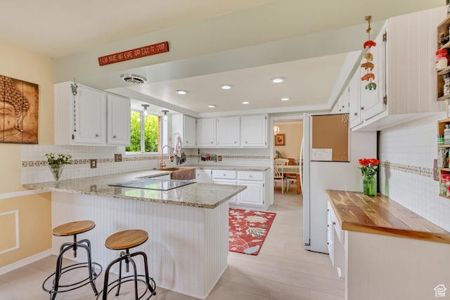 982 E 315 S, Orem, UT 84097 - kitchen featuring white cabinets, a peninsula, decorative backsplash, and cooktop