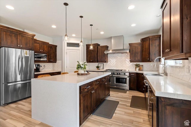 kitchen featuring appliances with stainless steel finishes, wall chimney exhaust hood, a sink, tasteful backsplash, and a kitchen island