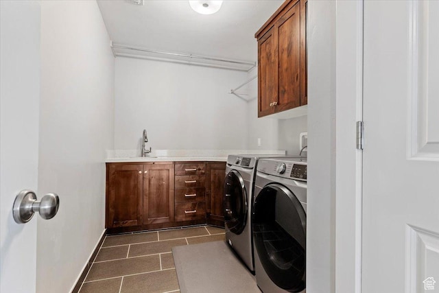 clothes washing area with washer and dryer, cabinet space, dark tile patterned floors, baseboards, and bar with sink