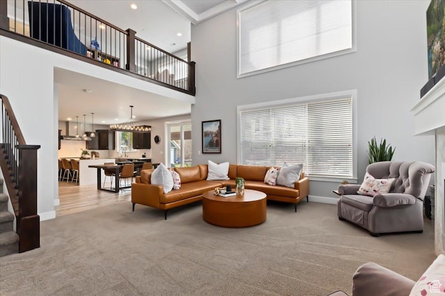 living area featuring light colored carpet, stairway, a high ceiling, recessed lighting, and baseboards