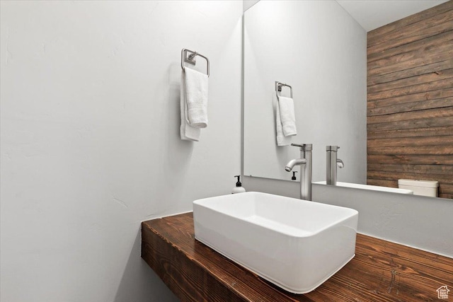 bathroom featuring a sink and wooden walls