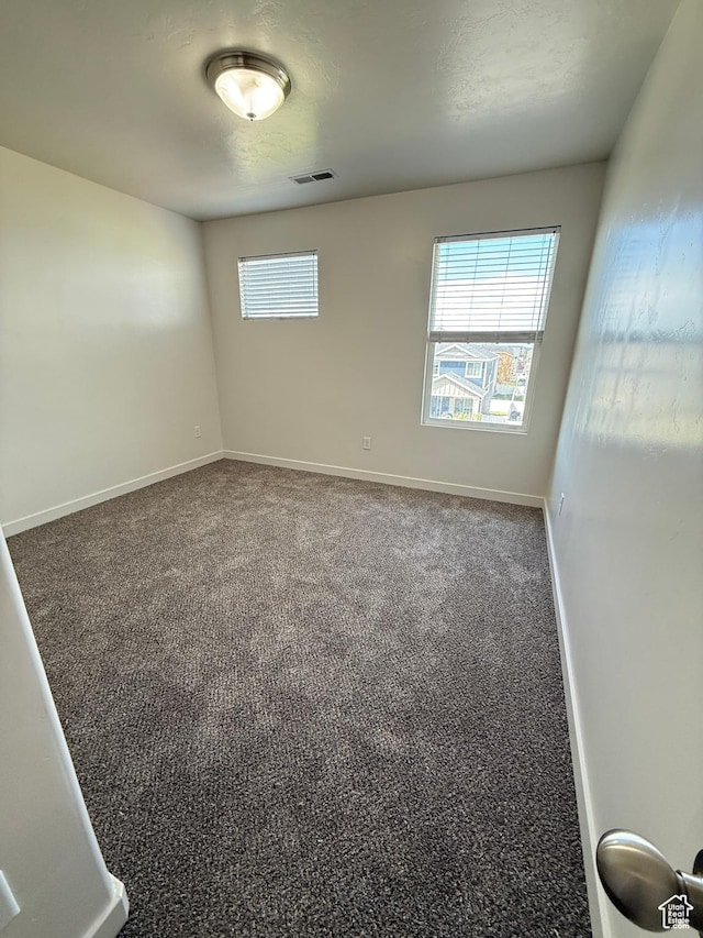 unfurnished room featuring baseboards, carpet floors, visible vents, and a wealth of natural light
