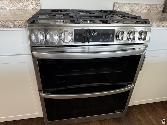 3678 W Sunrise Sky Ln S, South Jordan, UT 84009 - detailed view of range with two ovens, dark wood finished floors, light countertops, and white cabinetry
