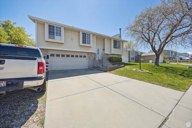 raised ranch with an attached garage, driveway, and a front yard