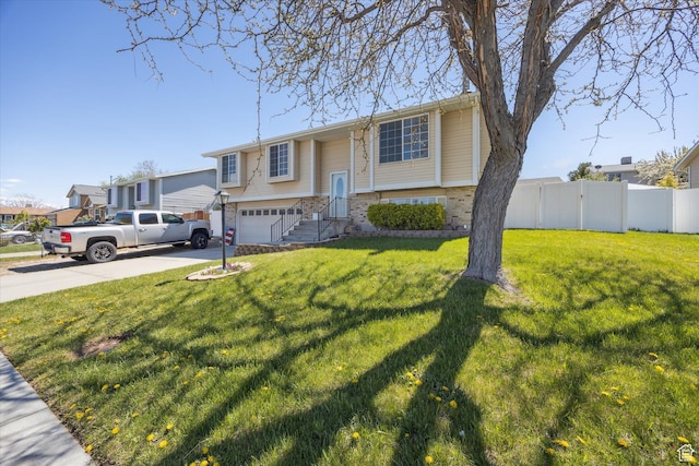 raised ranch with a garage, brick siding, fence, a front lawn, and concrete driveway