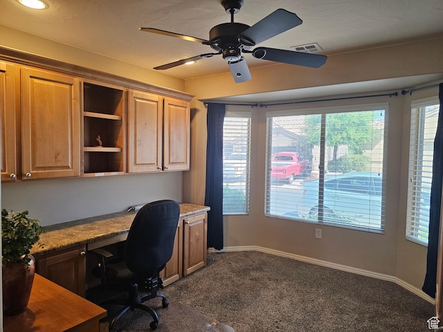 office area with built in study area, dark colored carpet, visible vents, and a healthy amount of sunlight