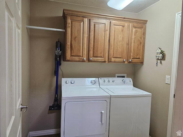 clothes washing area with washing machine and clothes dryer and cabinet space