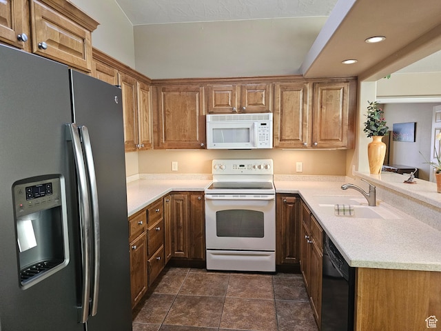 kitchen featuring light countertops, white appliances, a sink, and recessed lighting