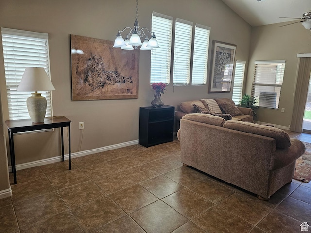 living area with dark tile patterned floors, vaulted ceiling, baseboards, and ceiling fan with notable chandelier