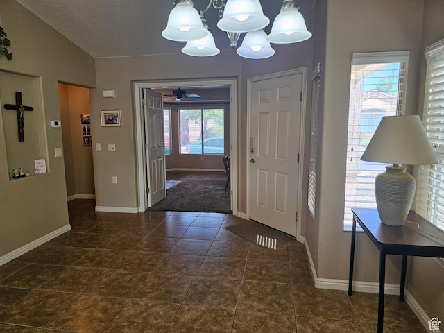 tiled foyer entrance with ceiling fan with notable chandelier and baseboards