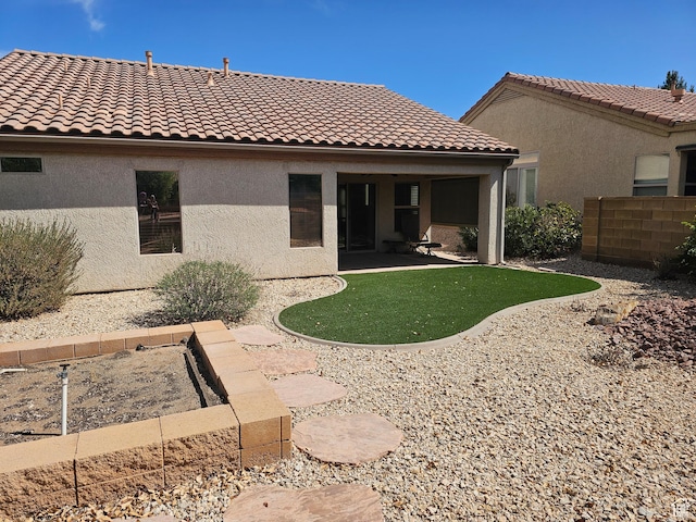 rear view of house featuring fence, a tiled roof, stucco siding, and a patio