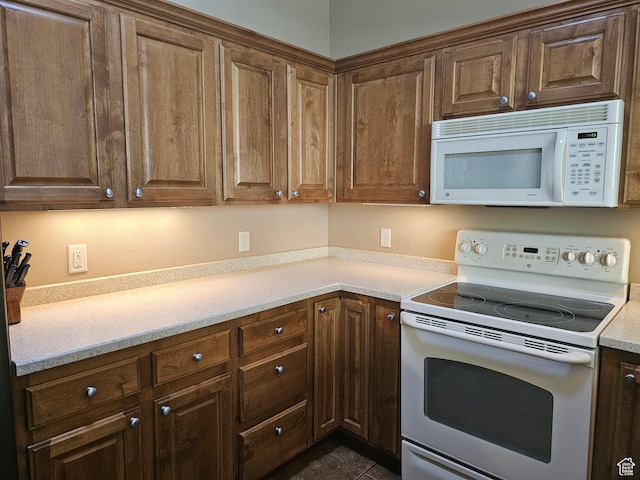 kitchen featuring light countertops, white appliances, and dark tile patterned floors