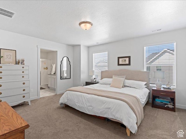 bedroom featuring a textured ceiling, visible vents, and light colored carpet