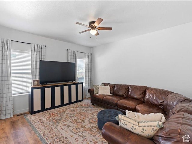living area with baseboards, wood finished floors, and ceiling fan