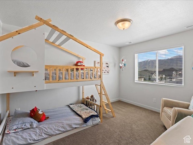 carpeted bedroom with a textured ceiling, baseboards, and visible vents