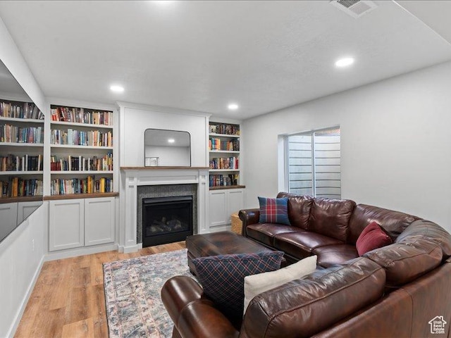 living room featuring a fireplace, recessed lighting, visible vents, and light wood-style flooring