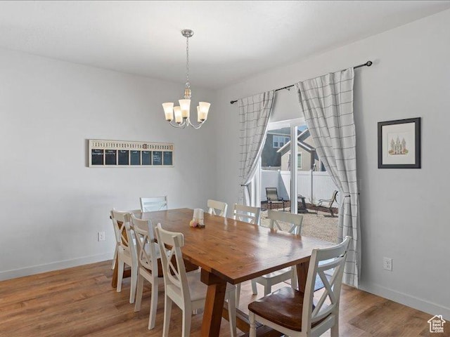 dining space featuring baseboards, wood finished floors, and an inviting chandelier